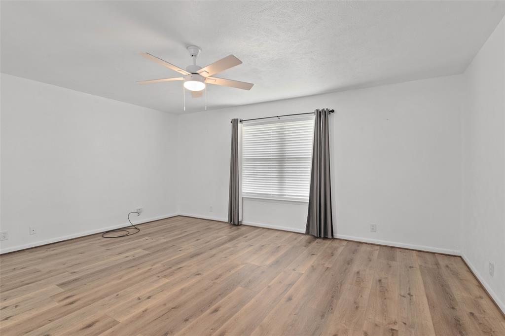 301 East 6th Street Krum, TX 76249 - Photo 7 of 29 Spacious bedroom with ceiling fan, wood-like flooring and large window allowing in plenty of natural light.