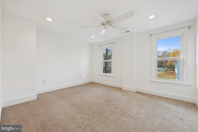 an empty room with windows and fan