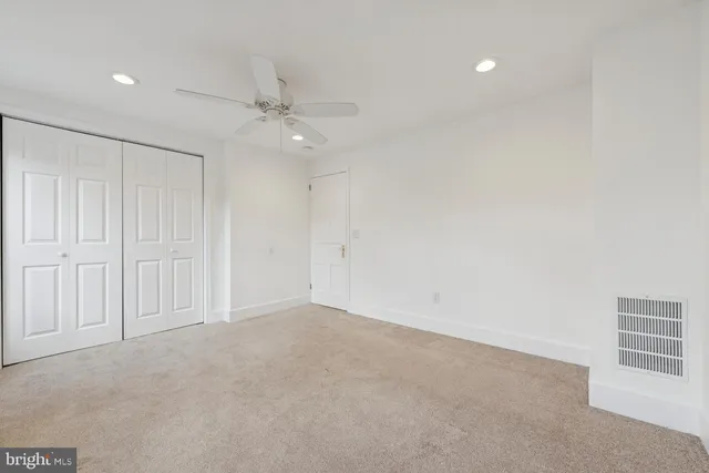 an empty room with a ceiling fan and window