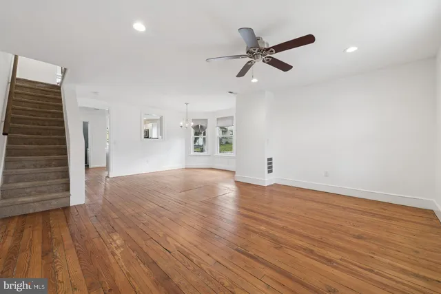 a view of empty room with wooden floor and ceiling fan