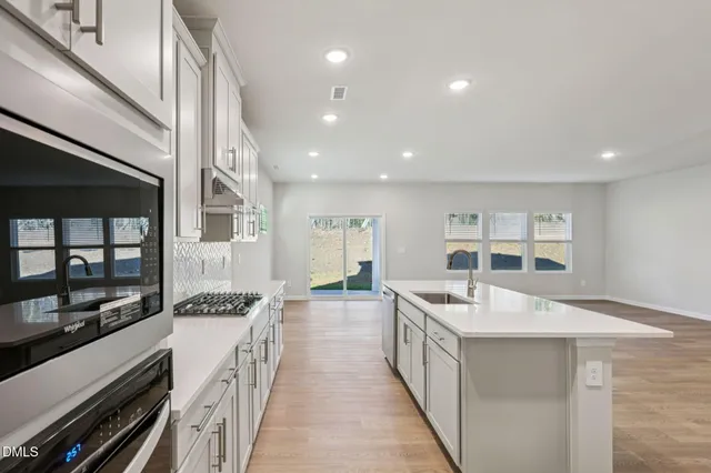 a kitchen with stainless steel appliances kitchen island granite countertop a refrigerator a sink and a stove