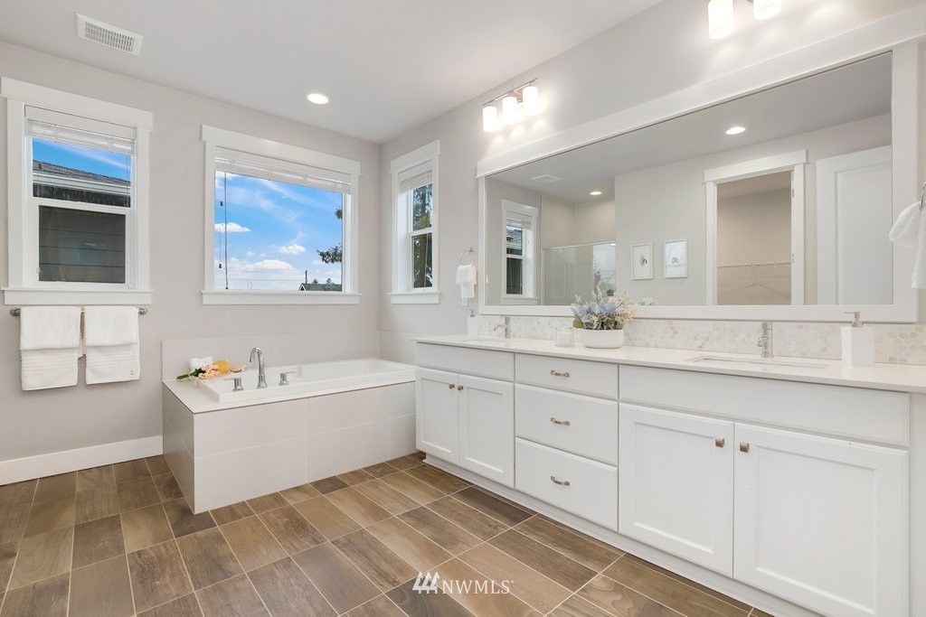 4327 223rd Place Southeast Bothell, WA 98021 - Photo 23 of 40 a spacious bathroom with double vanity a mirror a bathtub and a shower