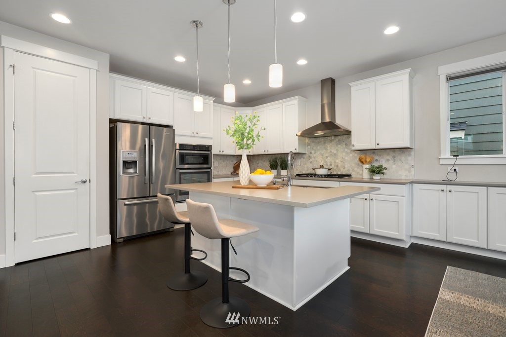4327 223rd Place Southeast Bothell, WA 98021 - Photo 9 of 40 a kitchen with stainless steel appliances granite countertop a refrigerator a sink dishwasher a stove and white cabinets with wooden floor
