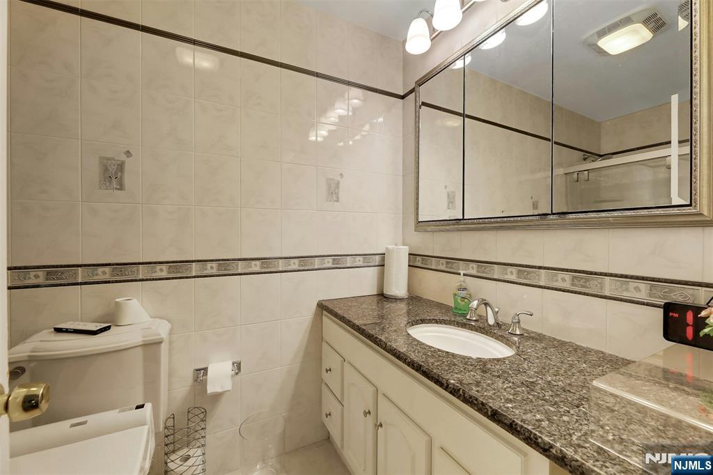 1093 Sheridan Street New Milford, NJ 07646 - Photo 36 of 45 a bathroom with a granite countertop sink a toilet and shower