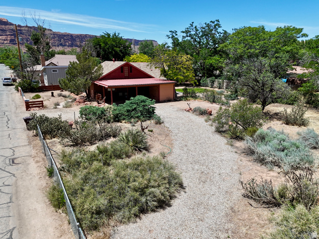 178 Walnut Lane Moab, UT 84532 - Photo 1 of 25 Red-roofed residence with an attached carport, gravel driveway, and surrounding desert landscaping