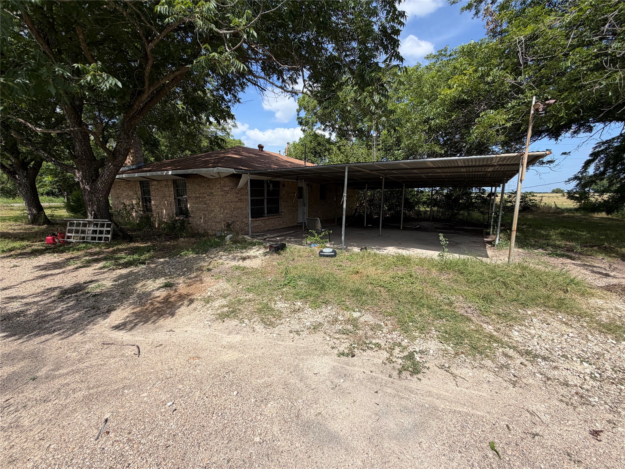 2501 Barnhardt Road Temple, TX 76502 - Photo 19 of 25 Mature trees shade this brick residence, featuring a functional carport and gravel driveway.