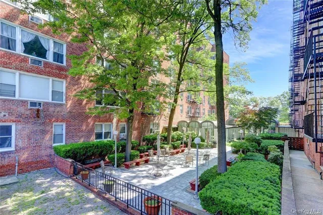 a view of a patio with table and chairs potted plants and large tree