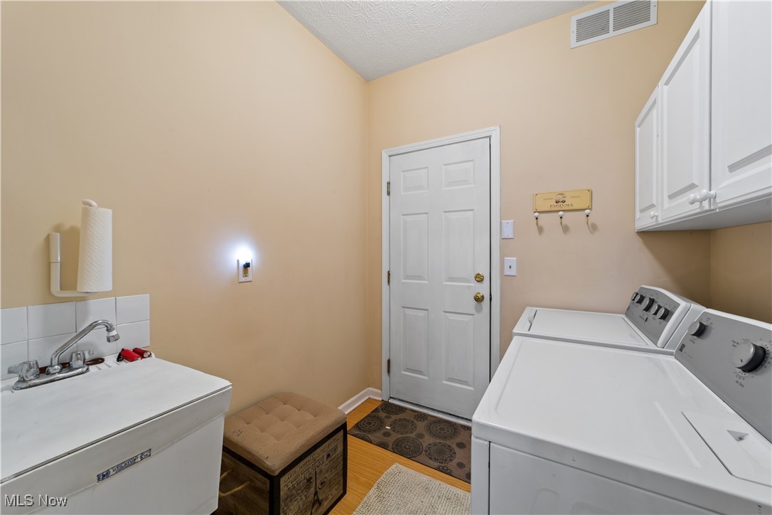 4461 Sexton Road Cleveland, OH 44105 - Photo 20 of 47 Laundry room with cabinet space, washer and dryer, and a textured ceiling