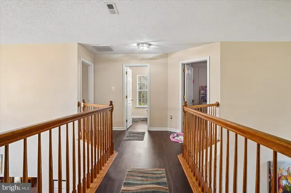 a view of a hallway with wooden floor and stairs