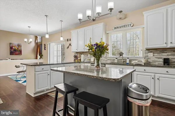 a kitchen with kitchen island granite countertop a sink cabinets and wooden floor