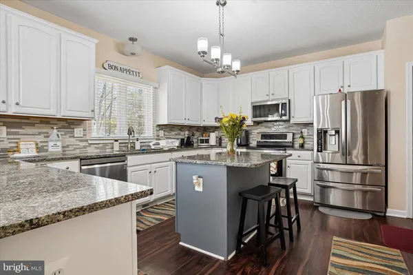 a kitchen with kitchen island granite countertop stainless steel appliances a refrigerator a stove a sink a center island and a center island
