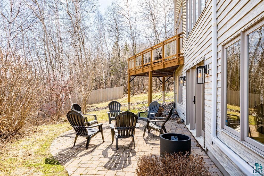4856 Kingston Street Duluth, MN 55804 - Photo 59 of 88 Paver patio with a fire pit, bordered by a wooden privacy fence and natural landscaping