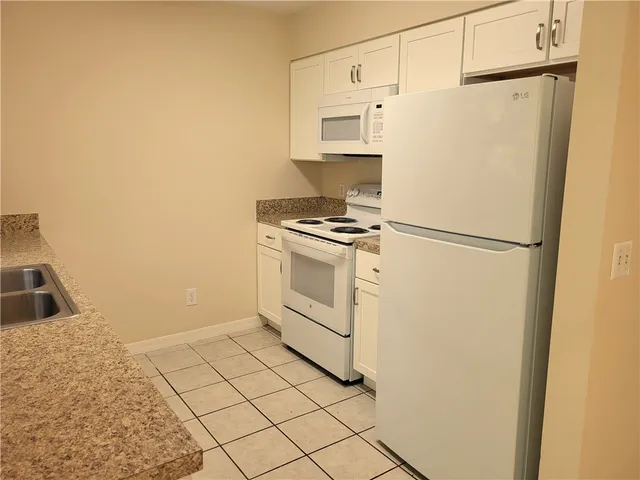 a white refrigerator freezer and a stove sitting inside of a kitchen