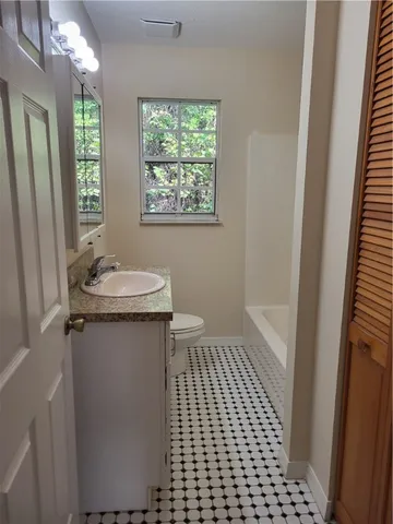 a bathroom with a sink a toilet a window and vanity