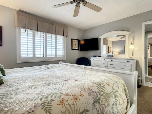 a bedroom with a bed a mirror and a flat tv screen on the dresser