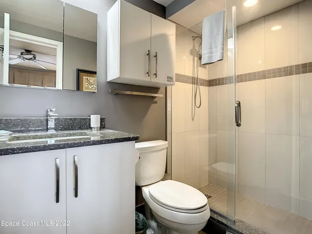 a bathroom with a granite countertop sink a toilet and a shower