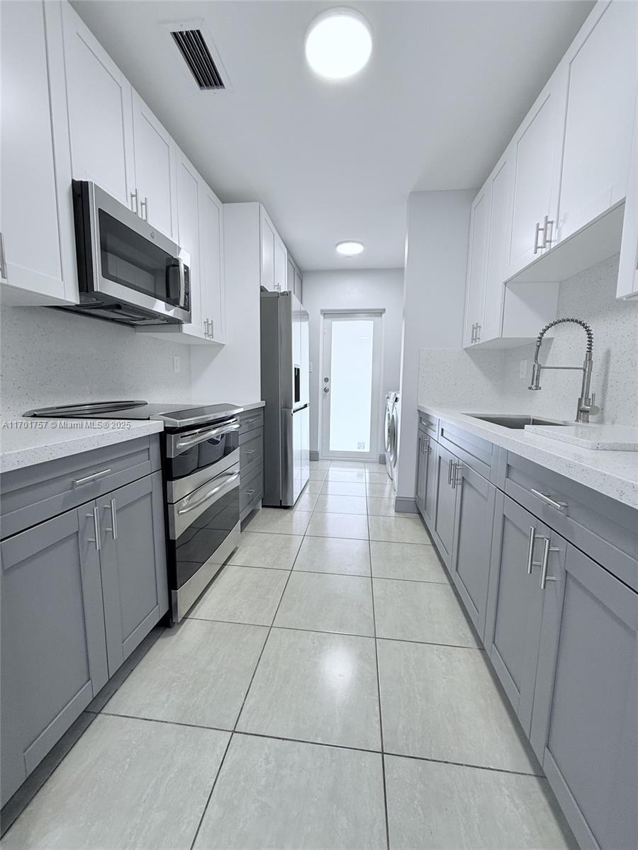 956 West 68th Street Hialeah, FL 33014 - Photo 10 of 21 a large kitchen with stainless steel appliances granite countertop a sink and cabinets