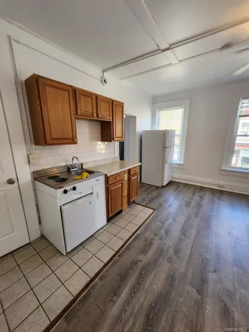 a kitchen with granite countertop a stove top oven a sink dishwasher and a refrigerator with wooden floor