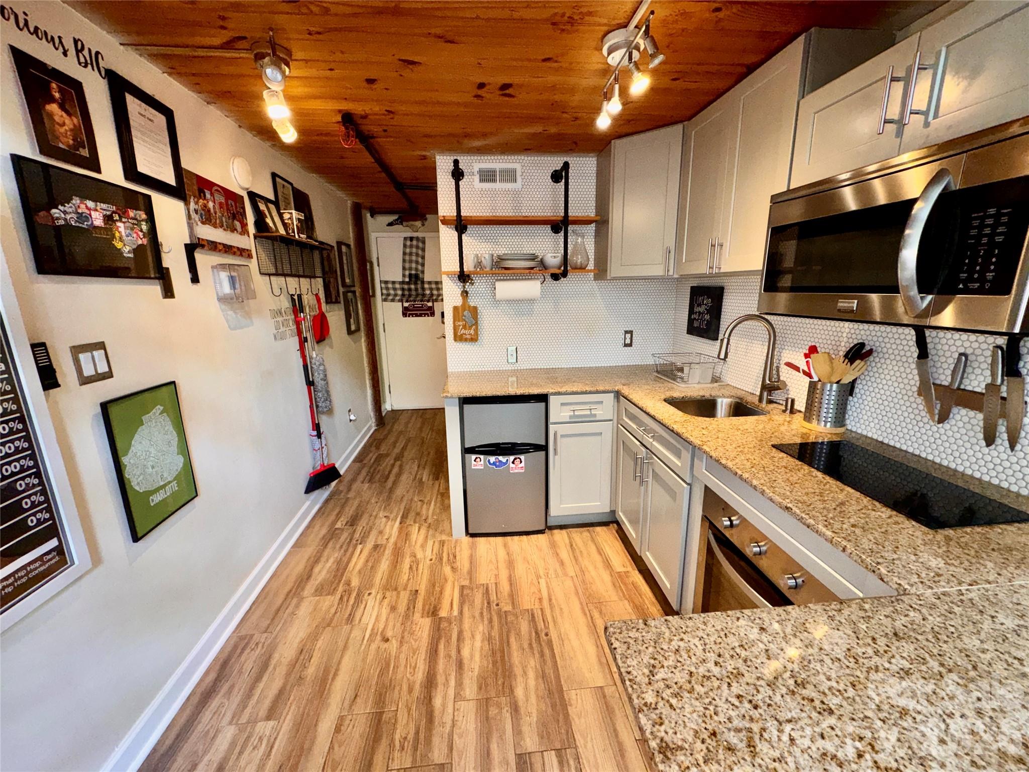 201 South Hoskins Road, Unit 132 Charlotte, NC 28208 - Photo 8 of 20 a kitchen with stainless steel appliances a microwave a stove a sink dishwasher and cabinets with wooden floor