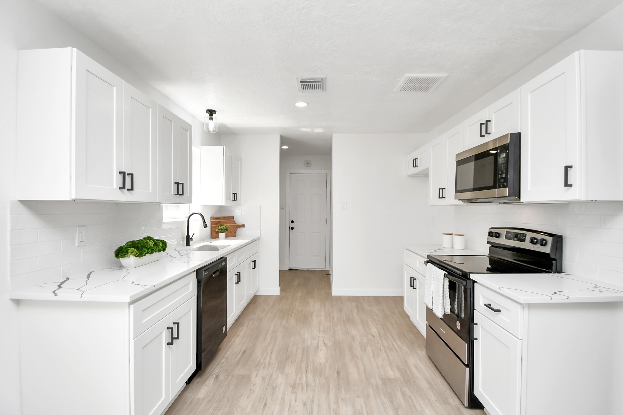 9912 Cardinal Street La Porte, TX 77571 - Photo 11 of 34 a kitchen with stainless steel appliances a white stove top oven a sink a refrigerator white cabinets and wooden floor