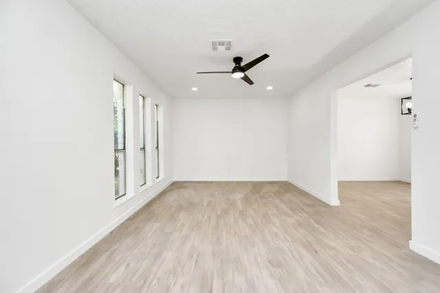 an empty room with wooden floor cabinet and windows
