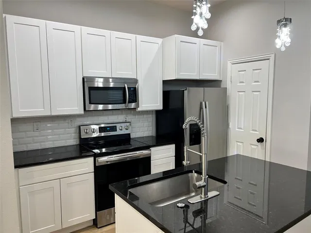 a kitchen with granite countertop a sink a counter top space appliances and cabinets