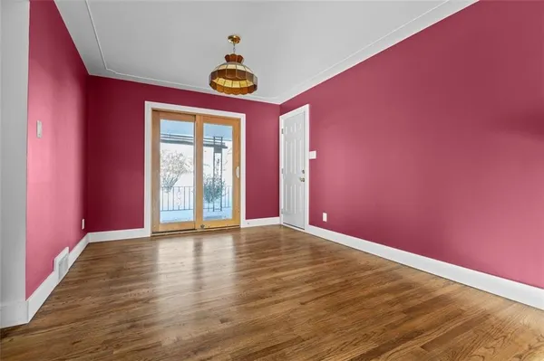 a view of an empty room with window and wooden floor