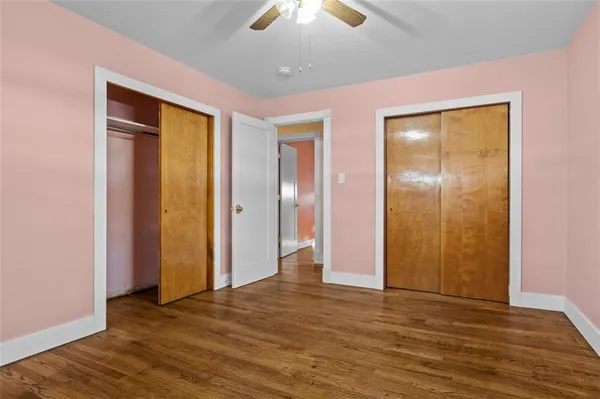 a view of an empty room with wooden floor and a chandelier fan