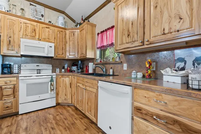 a kitchen with stainless steel appliances granite countertop a sink and cabinets with wooden floor