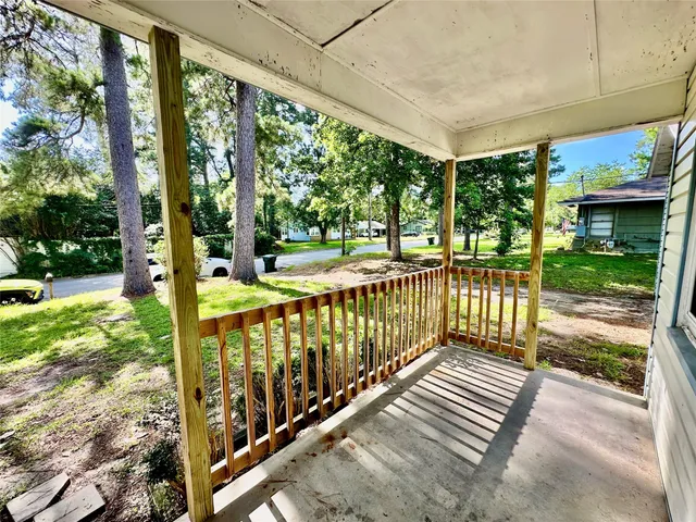 a view of a porch with wooden floor next to a yard