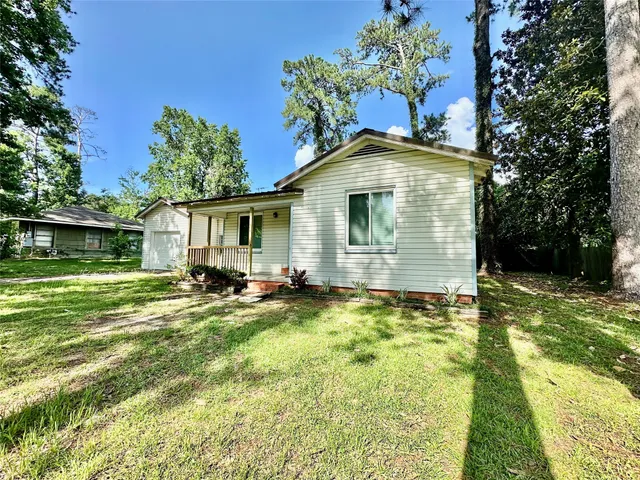 a front view of house with yard and trees in the background