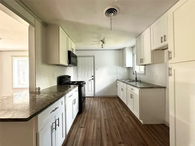 a kitchen with granite countertop a sink a counter space appliances and cabinets