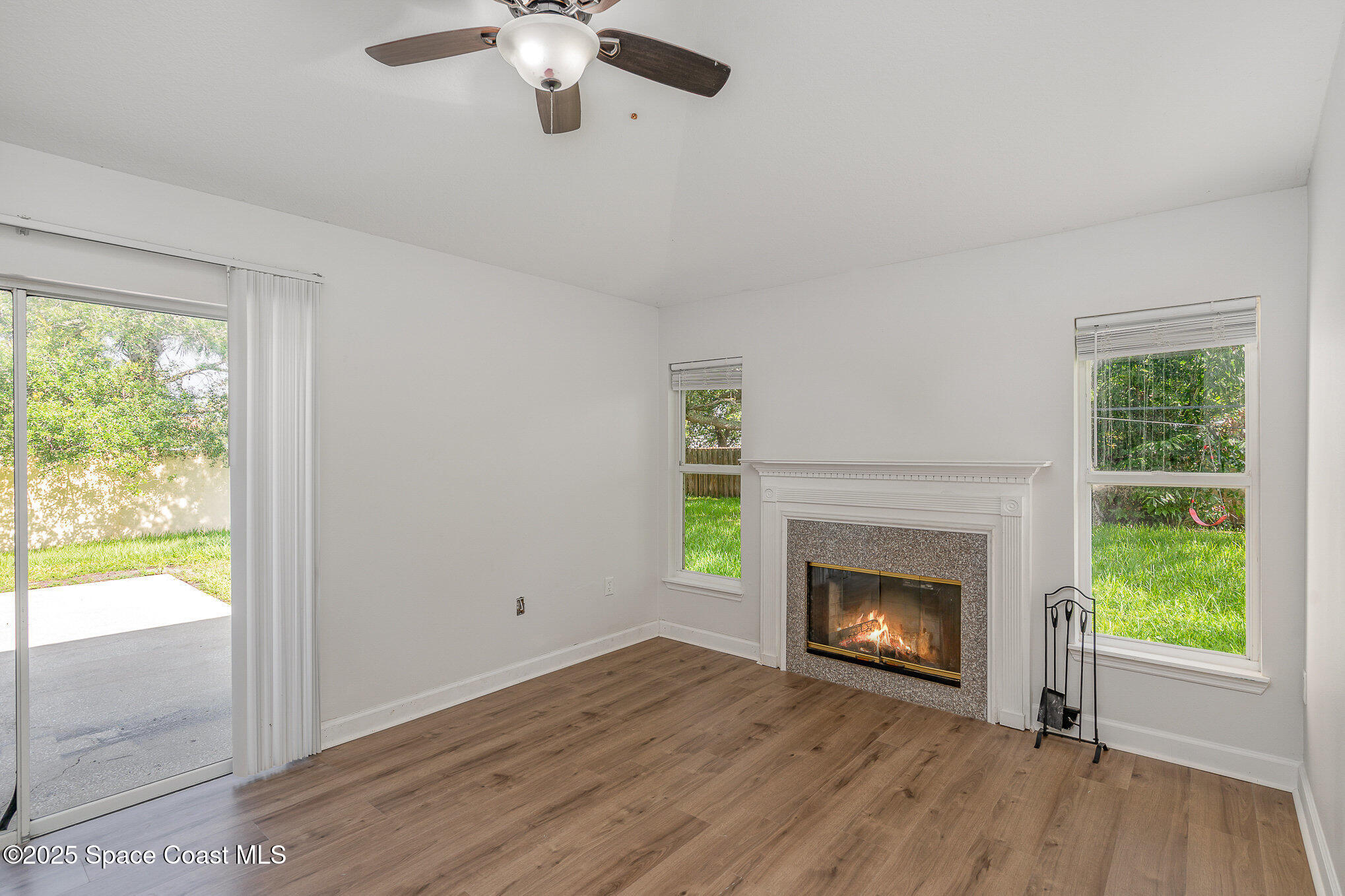 2143 Lansing Street Melbourne, FL 32935 - Photo 4 of 26 a view of an empty room with wooden floor fireplace and a window