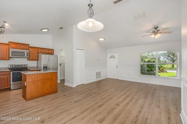 a view of kitchen with stainless steel appliances granite countertop a stove a sink dishwasher and a large window with wooden floor