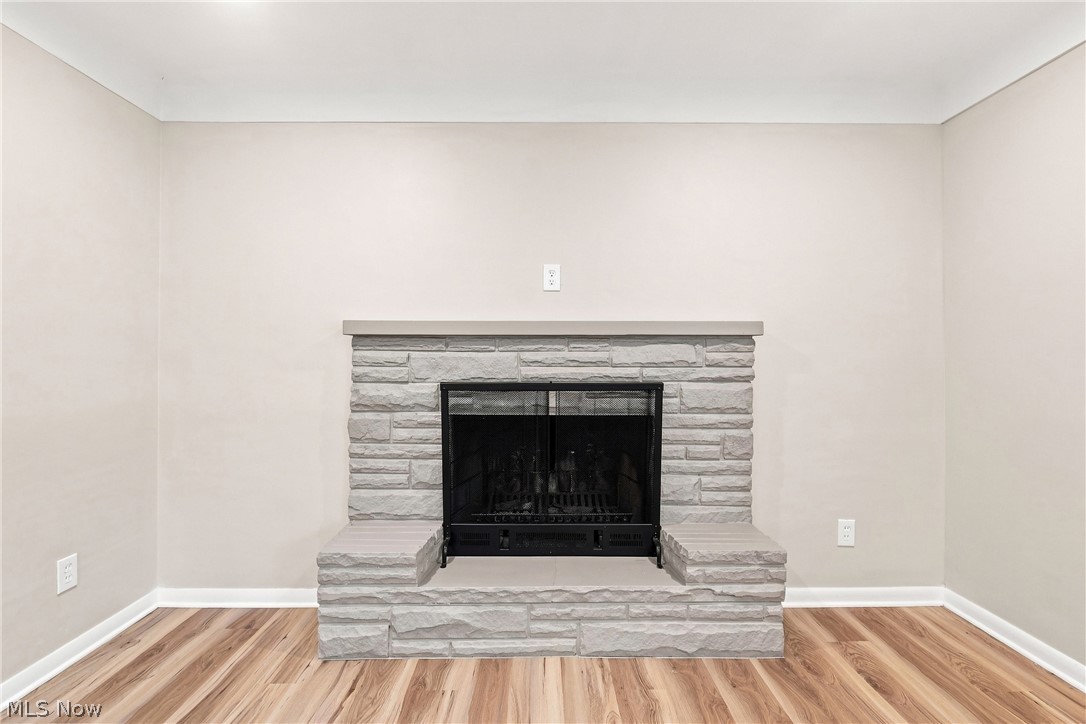 7524 Root Road North Ridgeville, OH 44039 - Photo 6 of 50 Stone surround fireplace with a black firebox, stone hearth, and wood-finish flooring