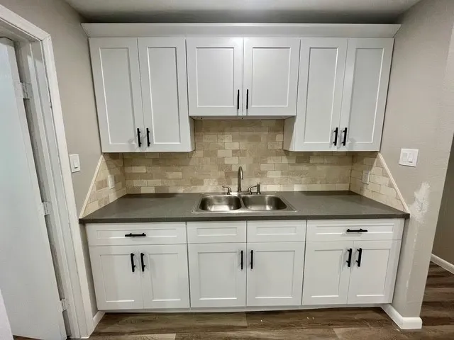 a kitchen with granite countertop white cabinets and a sink