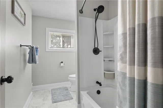 a bathroom with a toilet a sink a mirror and a window