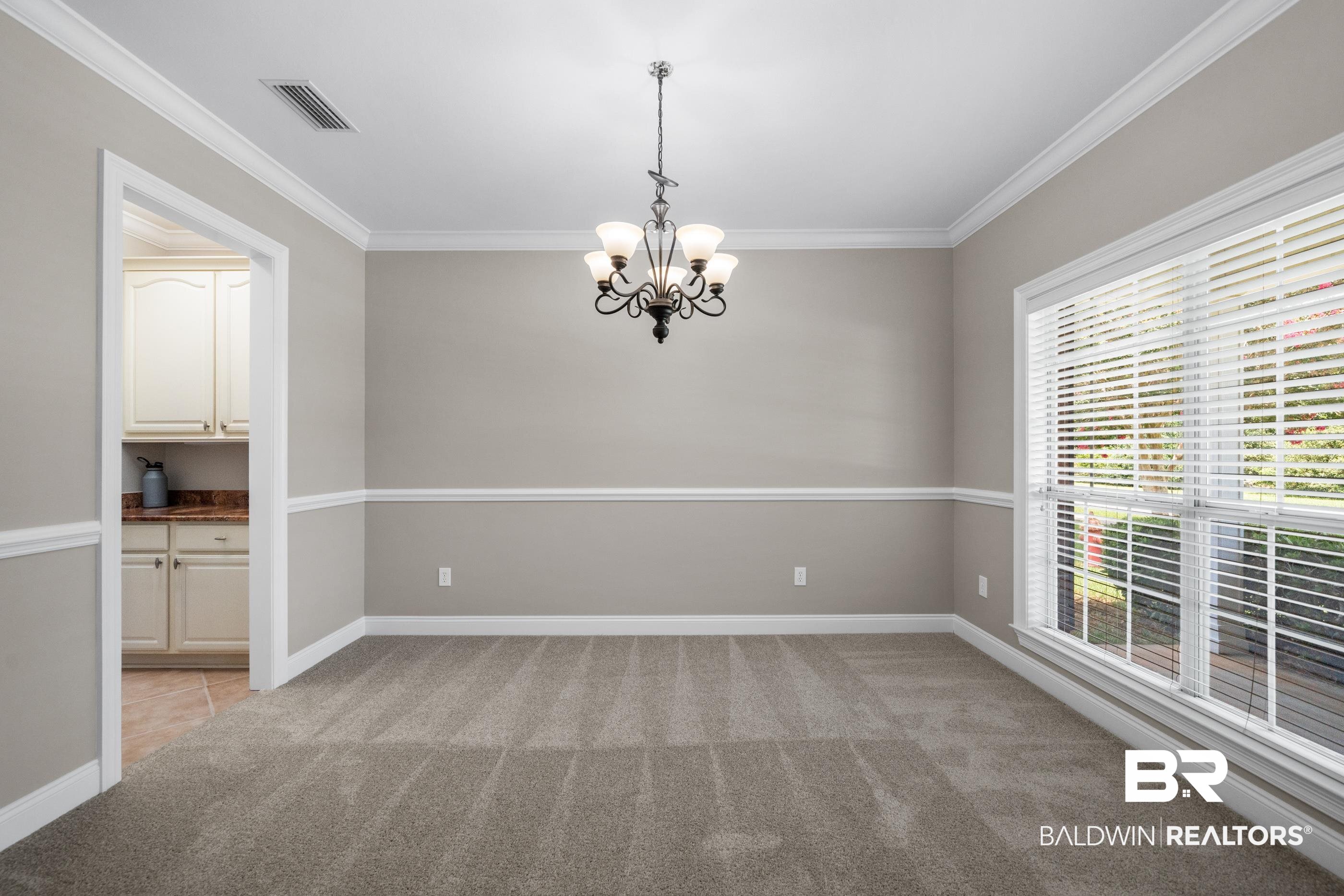 303 Savannah Circle Foley, AL 36535 - Photo 3 of 34 Neutral-toned room featuring a chandelier light fixture, crown molding, and chair rail detailing