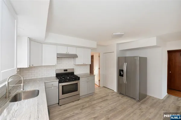 a kitchen with granite countertop a refrigerator and a sink