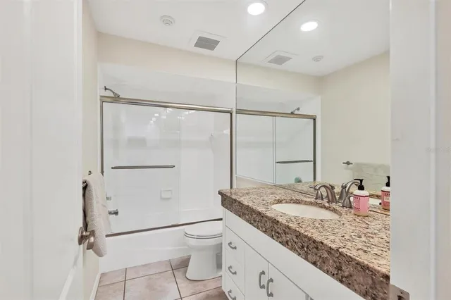 a bathroom with a granite countertop sink mirror vanity and toilet