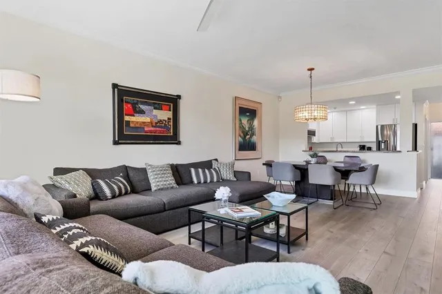 a living room with furniture kitchen view and a wooden floor
