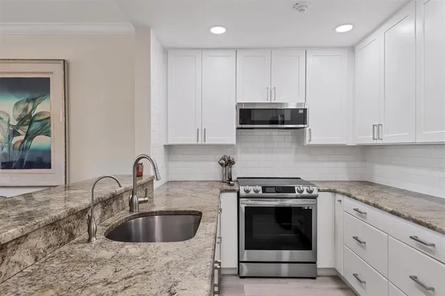 a kitchen with granite countertop a stove a sink and a microwave