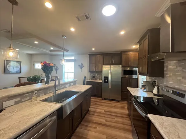 a kitchen with granite countertop kitchen island stainless steel appliances a sink stove and refrigerator