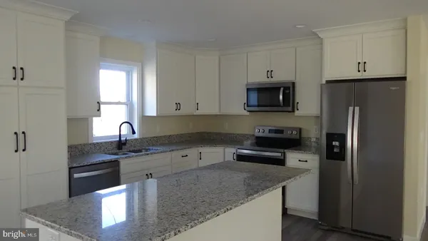 a kitchen with granite countertop a sink stove and refrigerator