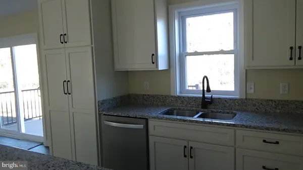 a kitchen with granite countertop white cabinets and window