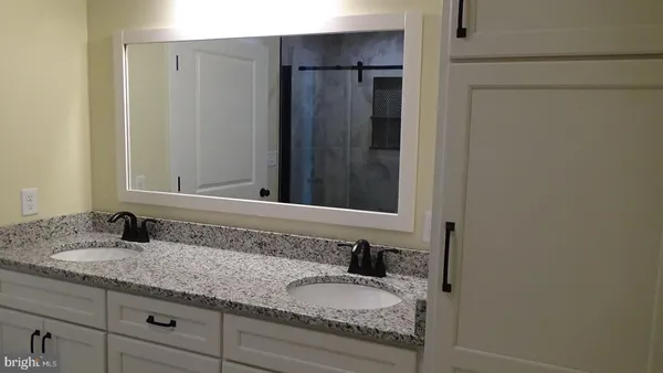 a bathroom with a granite countertop sink and a mirror
