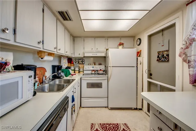 a kitchen with a refrigerator a stove top oven a sink and cabinets