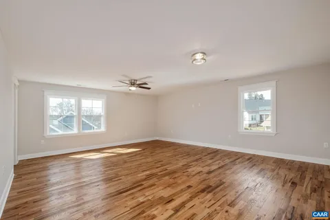 an empty room with wooden floor and ceiling fan