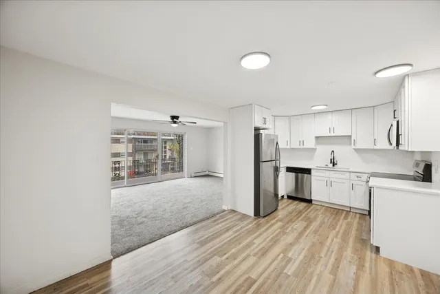 a open kitchen with white cabinets and wooden floor