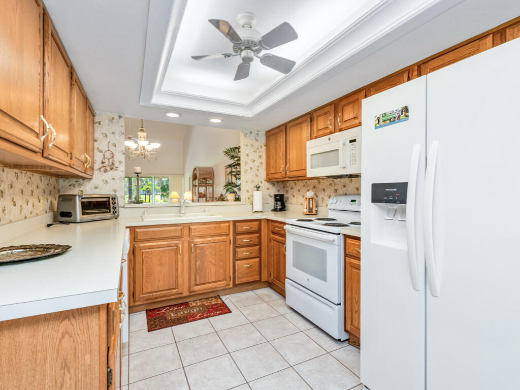 602 Augusta Boulevard, Unit 3 Naples, FL 34113 - Photo 5 of 8 a kitchen with stainless steel appliances granite countertop a refrigerator a sink dishwasher a stove with white cabinets and wooden floor